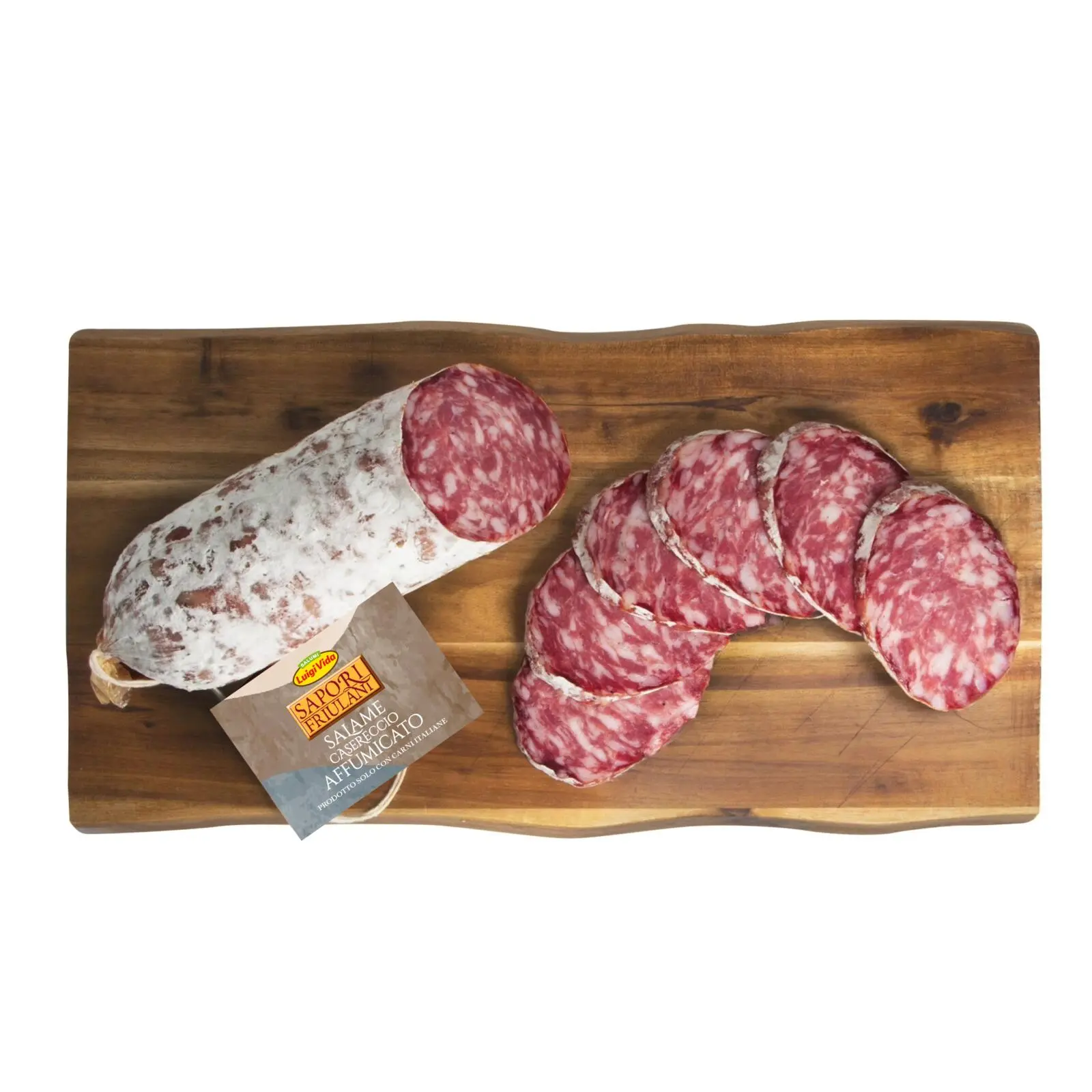 Un tagliere di legno espone un intero salame e diverse fette disposte accanto. L'interno marmorizzato del salame casereccio affumicato è splendidamente punteggiato, con un'etichetta attaccata per completare il suo fascino rustico.
